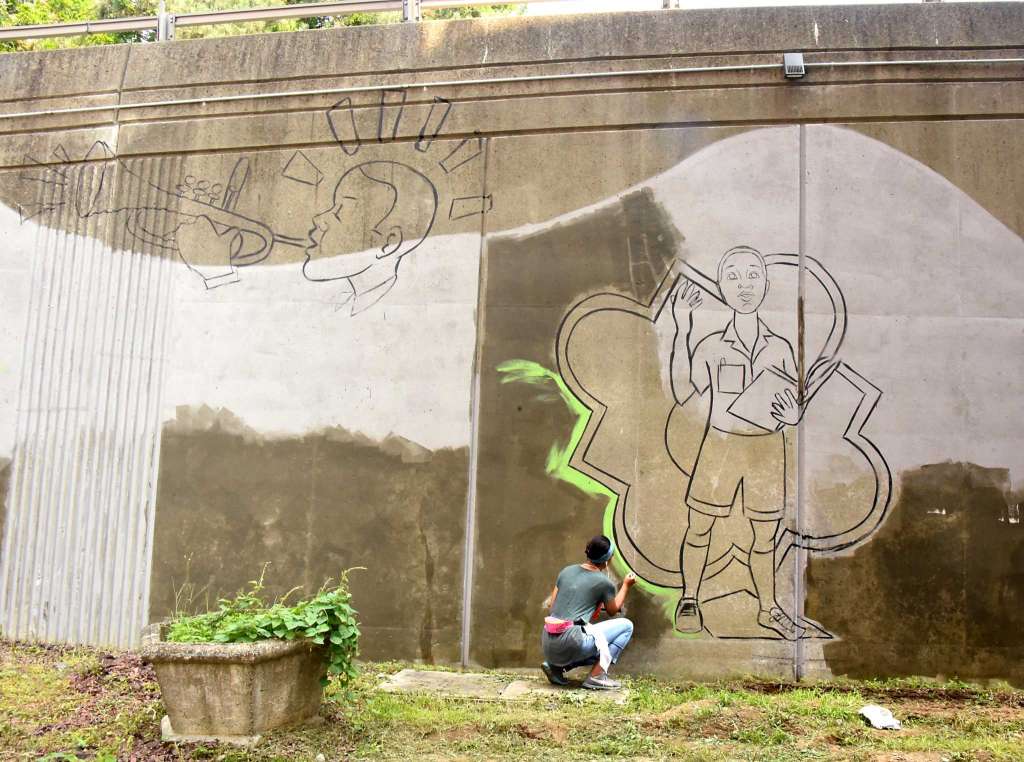 Liz Zunon adding green paint to her mural "Geraldine's Reverie"